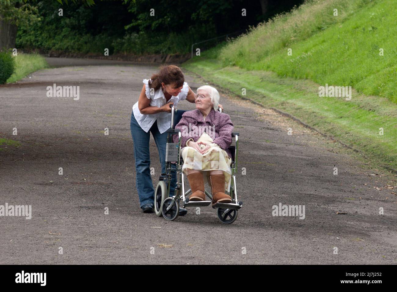 donna fuori con signora molto anziana in sedia a rotelle Foto Stock