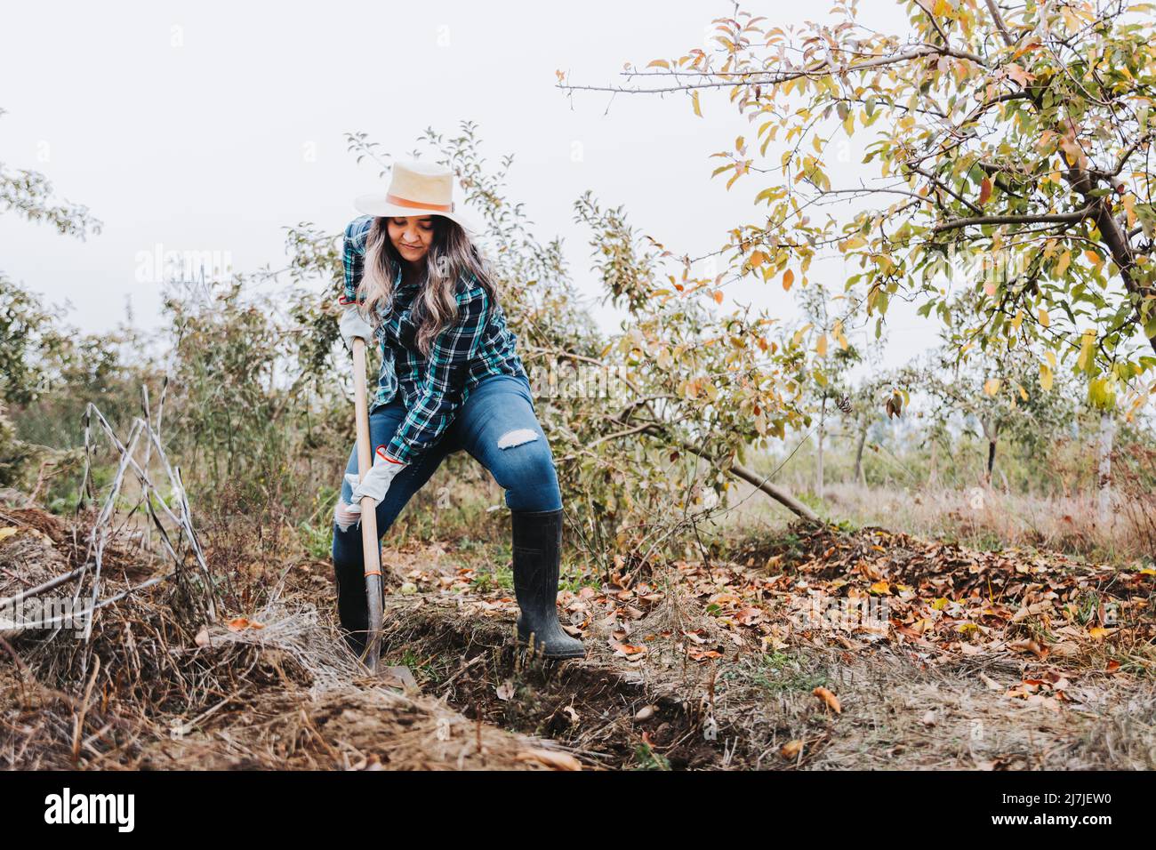 donna contadina che usa la pala per fare un solco nel terreno Foto Stock