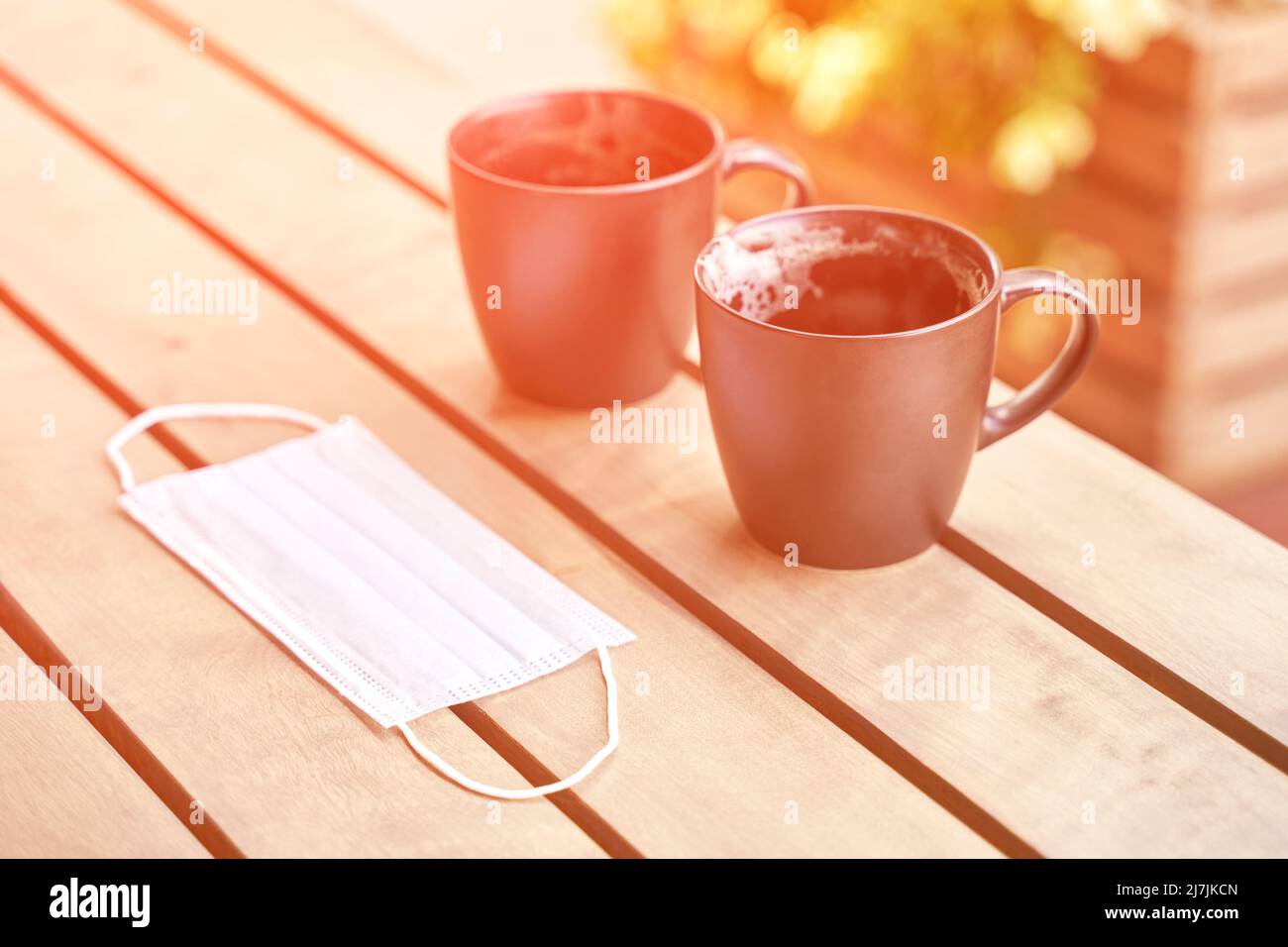 Due drink nella caffetteria all'aperto dopo un drink. Tazza sudicia dopo colazione. Maschera protettiva. latte in tazza. Pranzo atmosfera informale. Stile di vita accogliente mattina. Nessuna gente Foto Stock