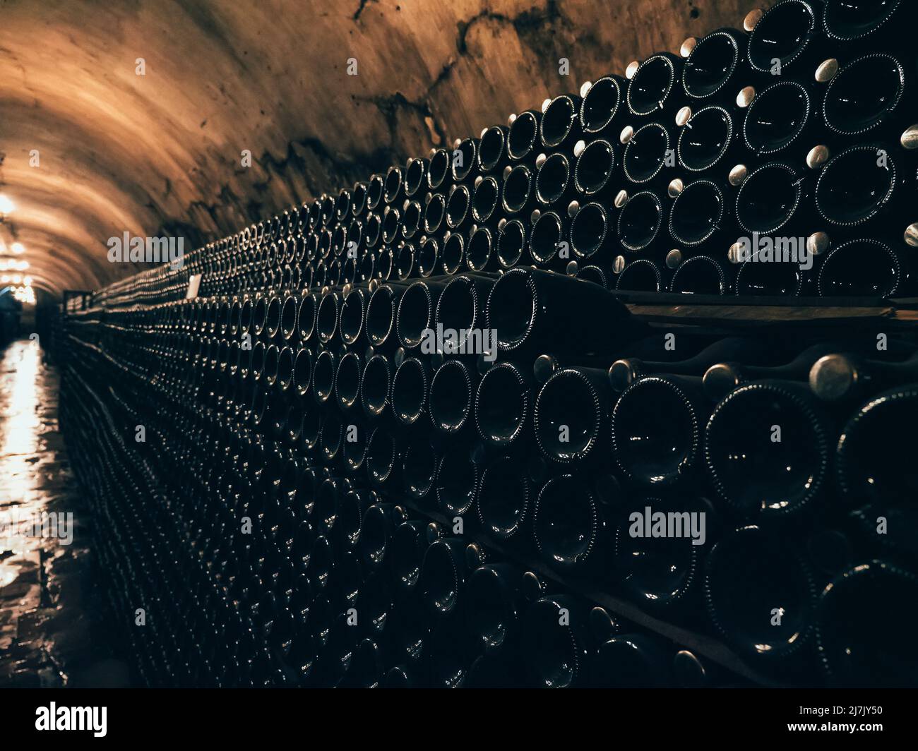 Molte bottiglie di vetro con vino in cantina sotterranea in cantina. Foto Stock