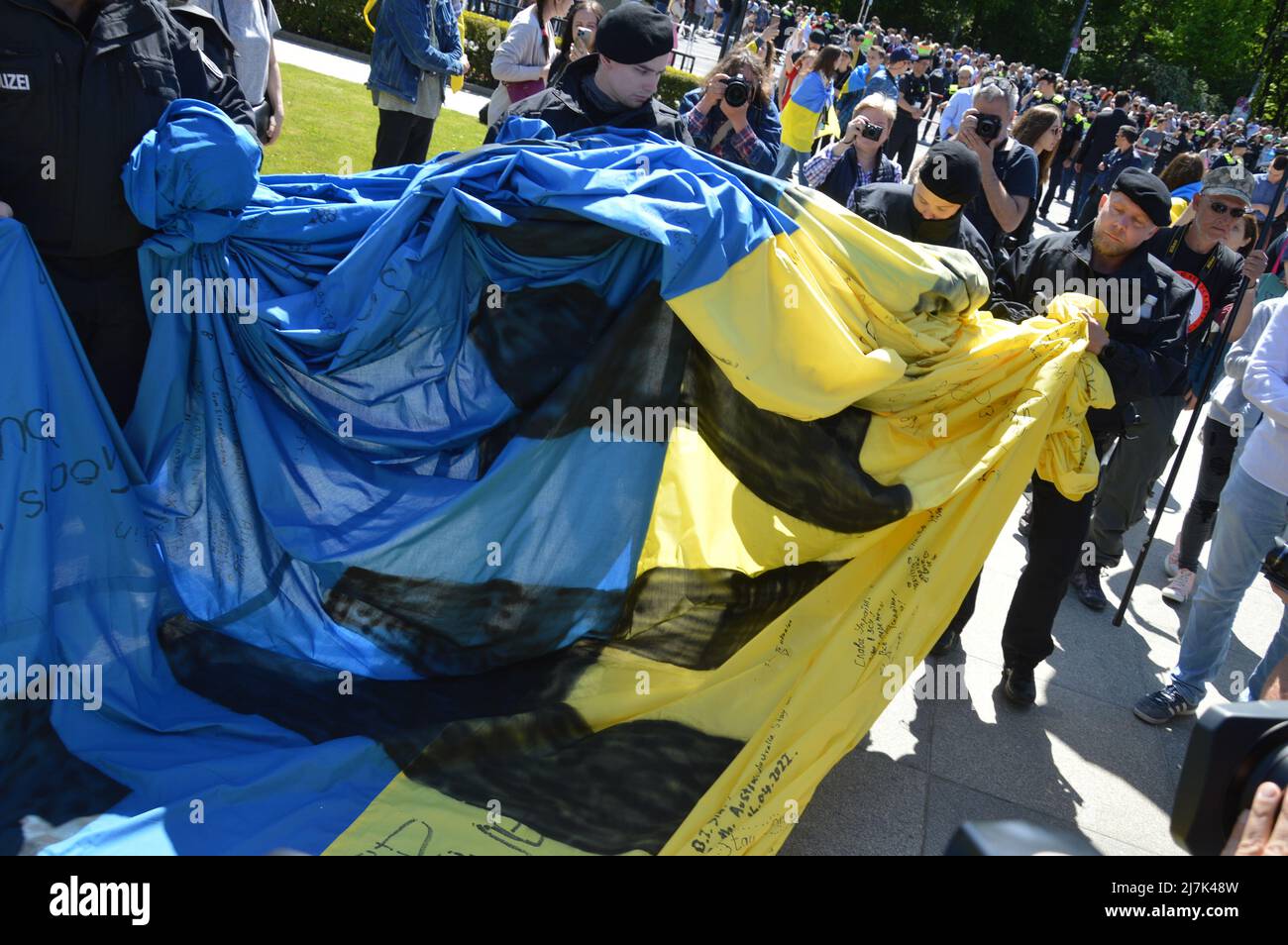 La polizia fa rotolare una bandiera Ucraina gigante mostrata dai dimostranti al Memoriale di guerra sovietico a Tiergarten, nel centro di Berlino, Germania - 8 maggio 2022. Foto Stock