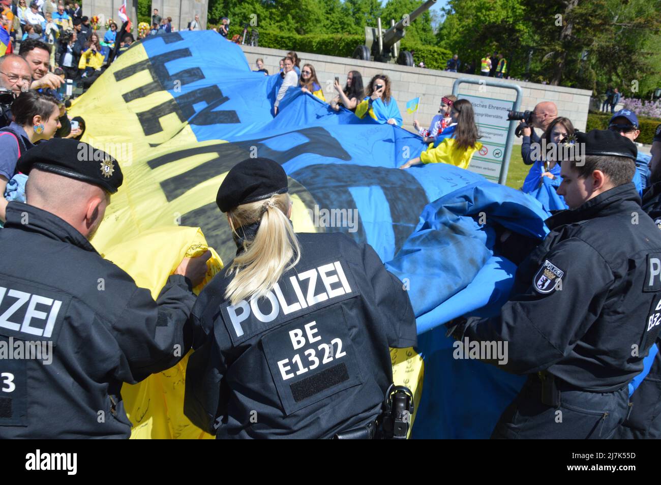 La polizia fa rotolare una bandiera Ucraina gigante mostrata dai dimostranti al Memoriale di guerra sovietico a Tiergarten, nel centro di Berlino, Germania - 8 maggio 2022. Foto Stock