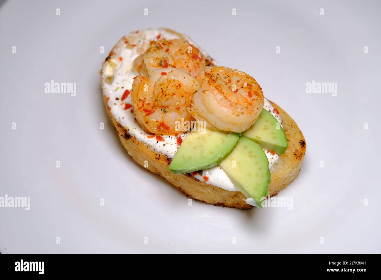 Sandwich all'avocado, con stagame e gamberetti su sfondo bianco macro close up Foto Stock