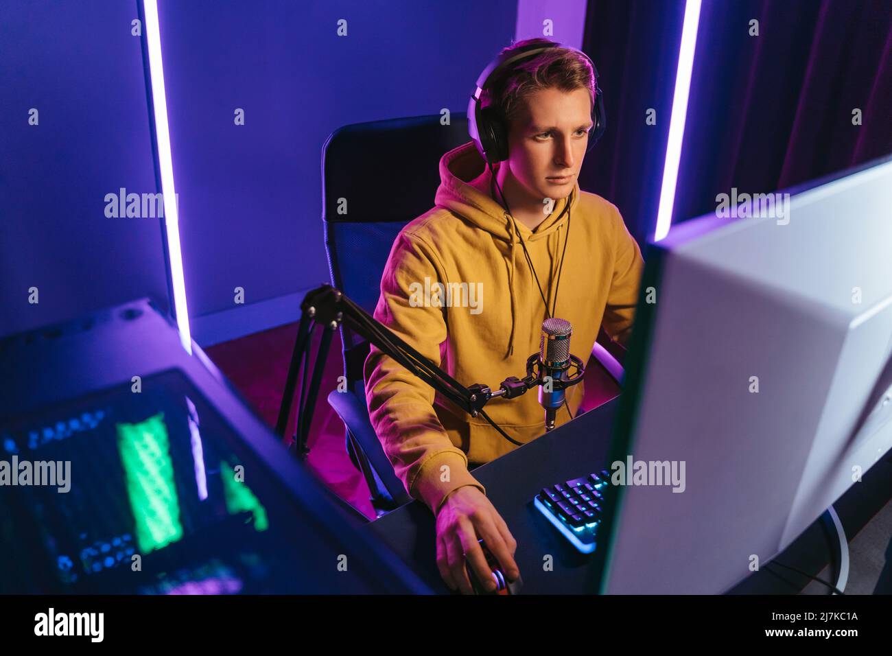 Torneo di eport in streaming per giovani giocatori professionisti con microfono e cuffie. Videogamer competitivo che gioca a videogame online su un potente PC a casa. Vista sito, colore neon. Concetto di Cyber sport Foto Stock