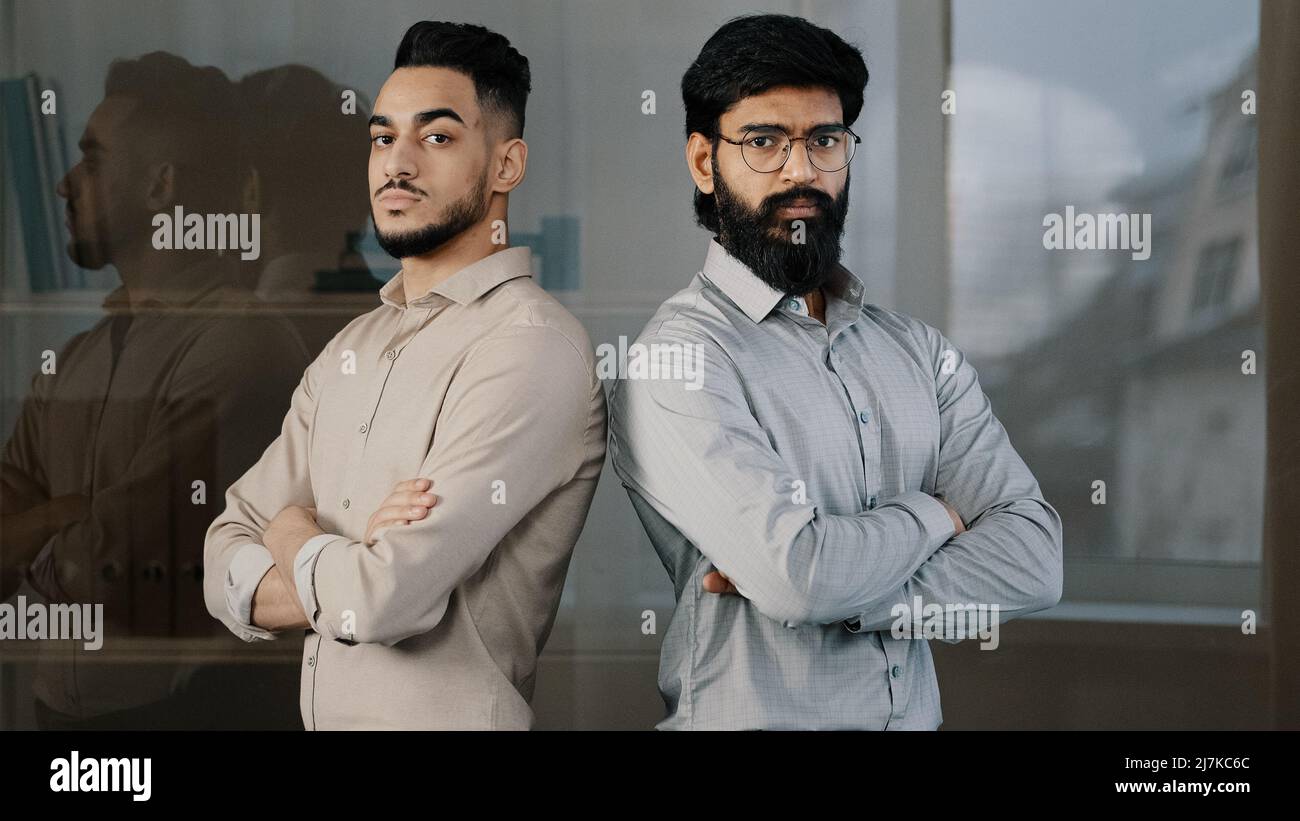 Coppia multirazziale diversi uomini d'affari colleghi colleghi colleghi colleghi maschi colleghi partner arabo barbato uomo in occhiali ispanico giovane ragazzo in piedi al coperto Foto Stock
