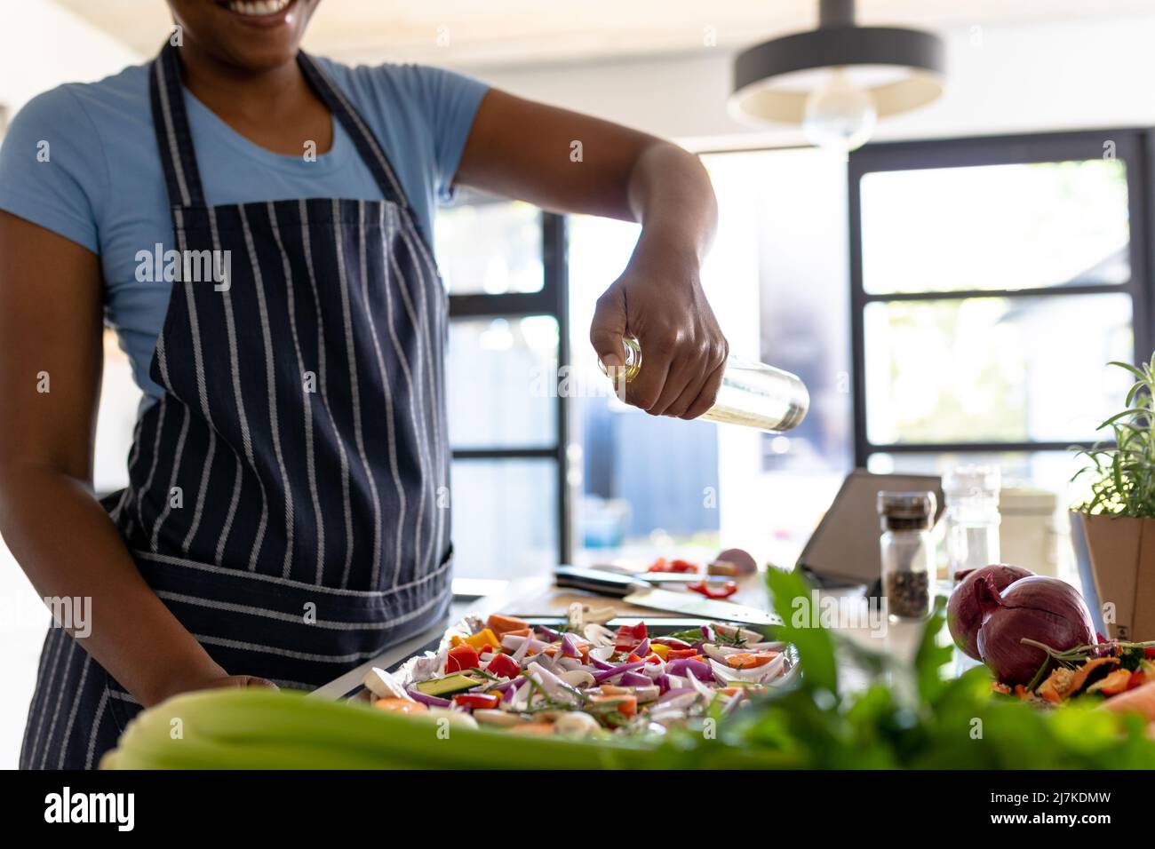 Metà sezione della donna afroamericana medio adulta che prepara il cibo in cucina a casa Foto Stock