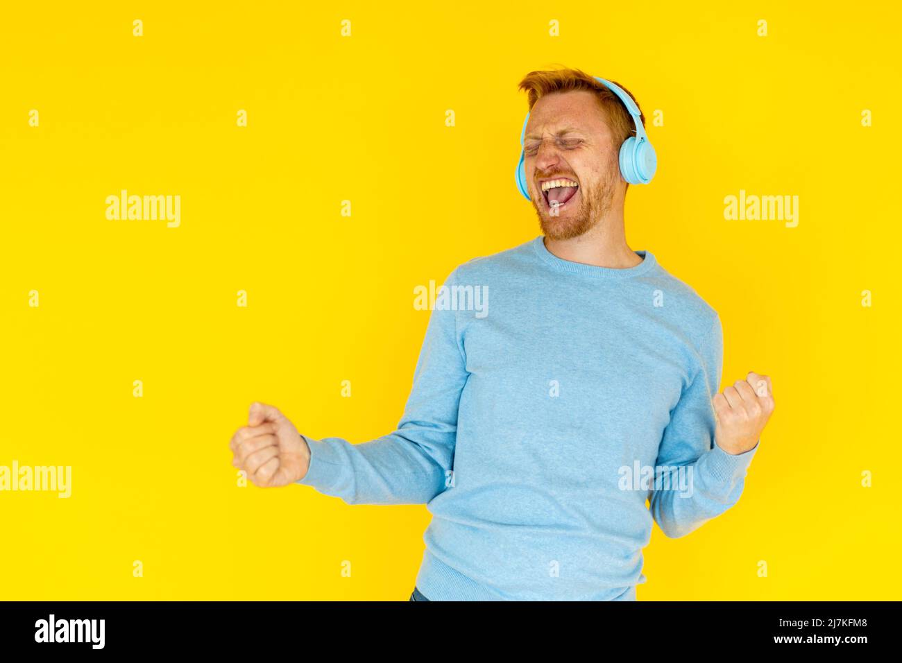 Felice giovane adulto ispanico latino uomo ballare su sfondo giallo Foto Stock