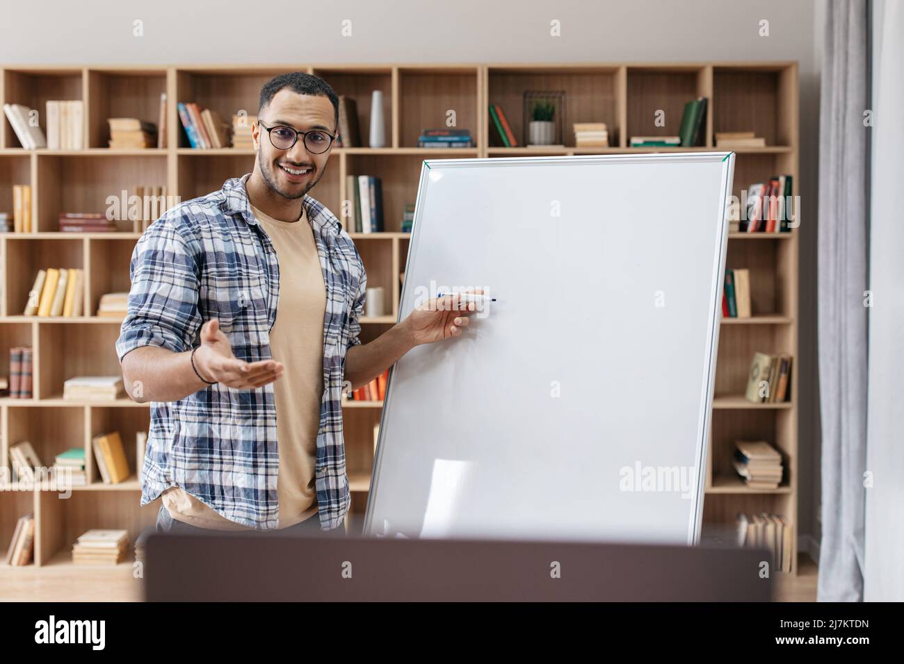 Concetto di presentazione. Ritratto del manager maschile felice in piedi vicino bianco lavagna vuota e puntando allo spazio di copia Foto Stock