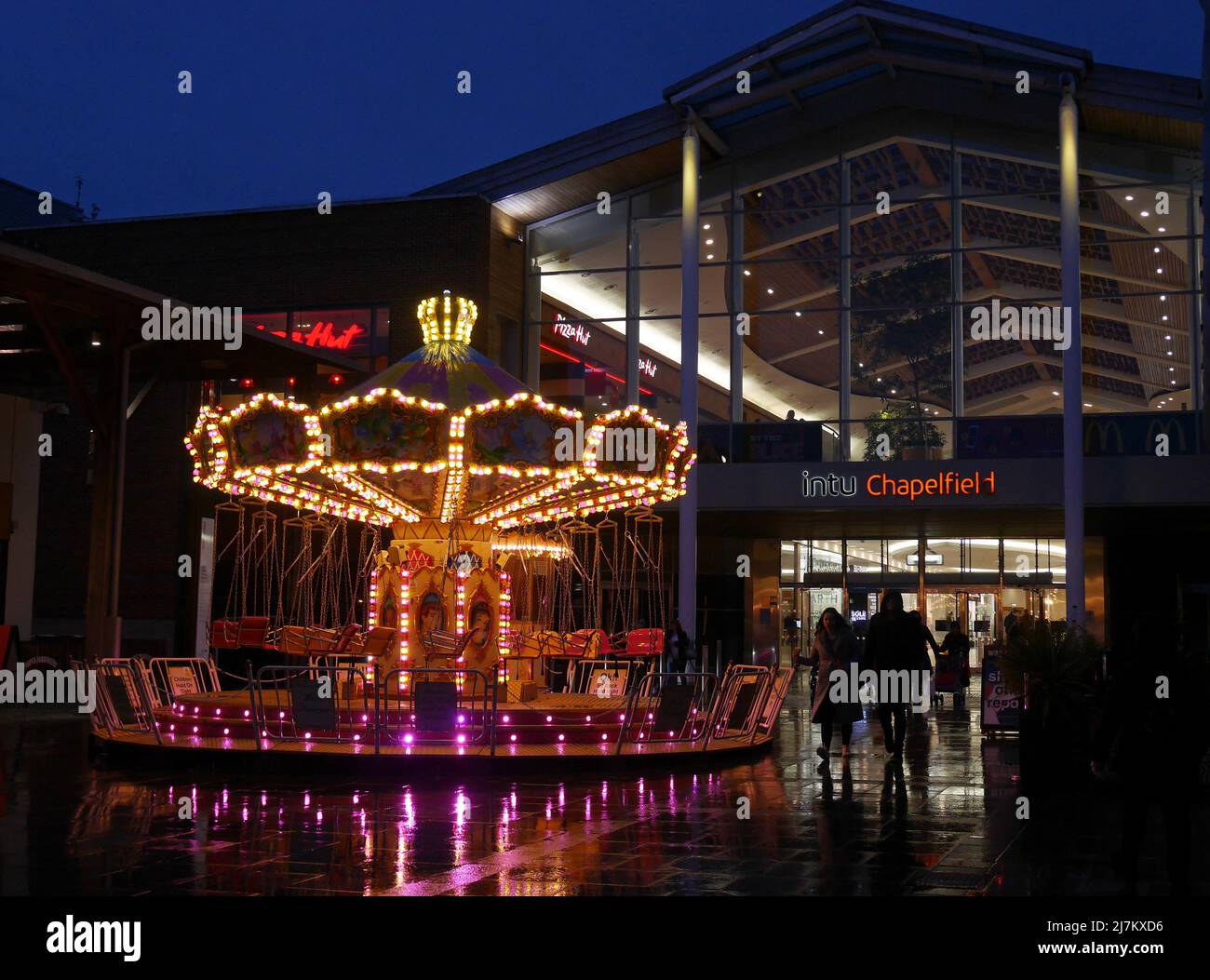Giostra per bambini illuminata di notte, fuori dal centro commerciale Chapelfield nella città di Norwich, Norfolk, Inghilterra, Regno Unito Foto Stock