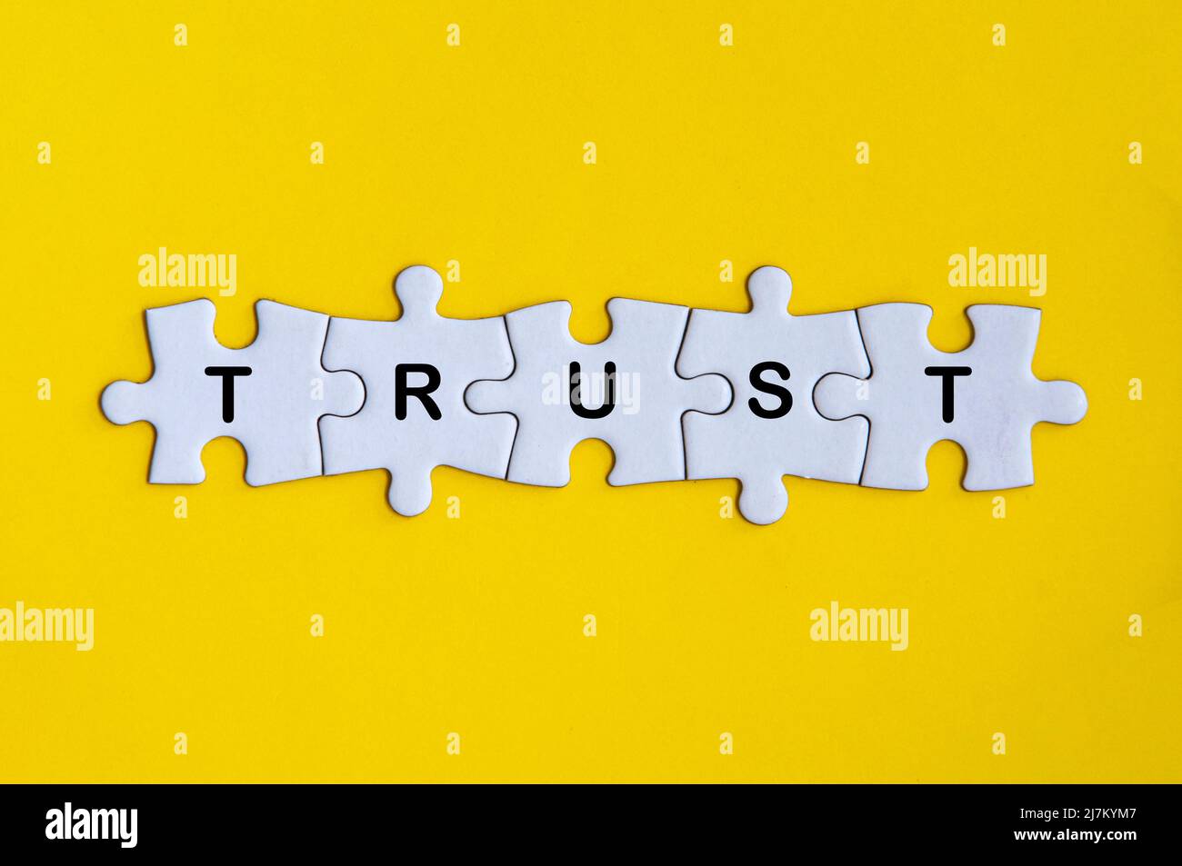 Parola fiducia manca puzzle jigsaw su sfondo giallo copertina. Concetto di fiducia Foto Stock