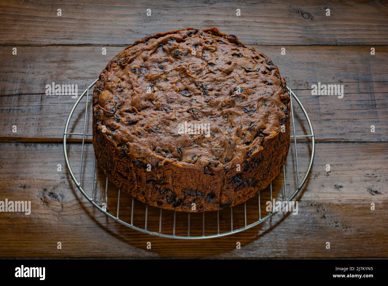 Torta di frutta fresca appena sfornata su una griglia di raffreddamento a filo, su una superficie di lavoro rustica in legno. Foto Stock