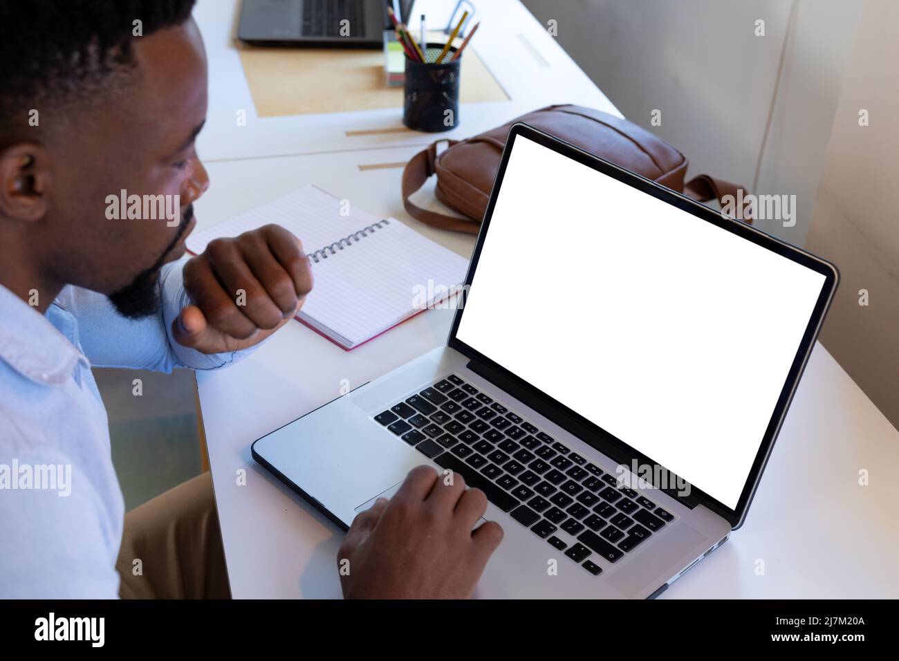 Uomo d'affari afro-americano medio adulto che usa un laptop con schermo vuoto mentre lavora in ufficio Foto Stock