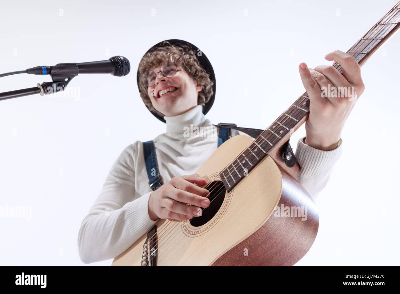 Ritratto di giovane emotiva, musicista che suona chitarra acustica e canti. Concetto di arte, musica, stile e creazione Foto Stock