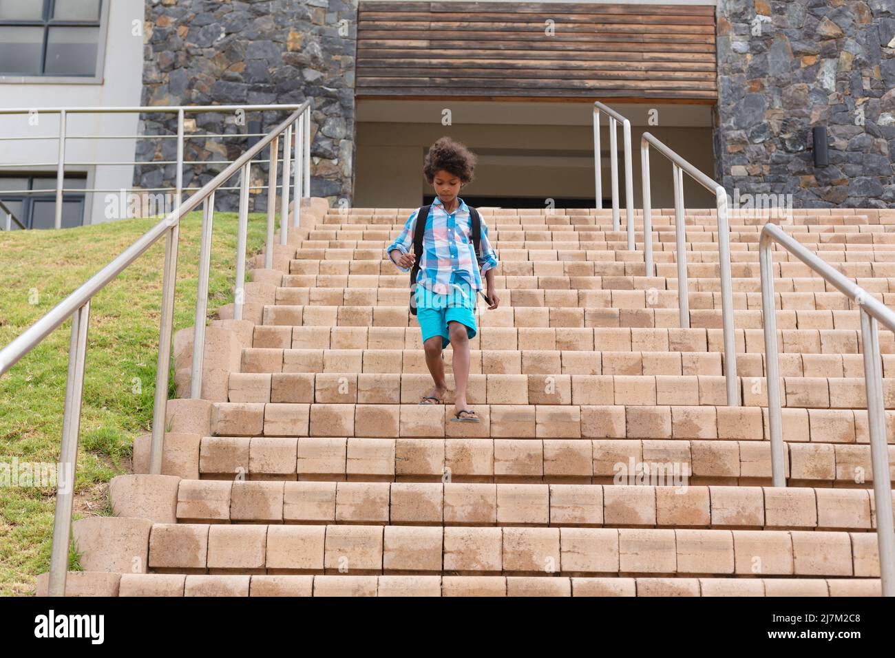 Tutta la lunghezza di scolaro elementare afroamericano che si sposta giù i passi di costruzione della scuola Foto Stock