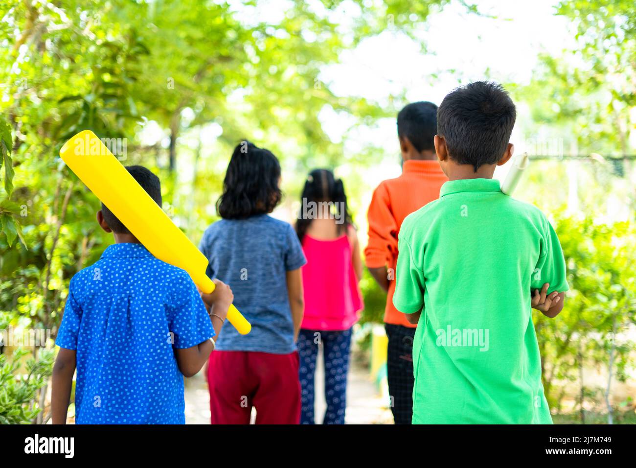 Torna indietro vista di bambini adolescenti che vanno a casa dopo aver giocato a cricket al parco - concetto di vacanze week-end, attività di svago e la convivenza Foto Stock