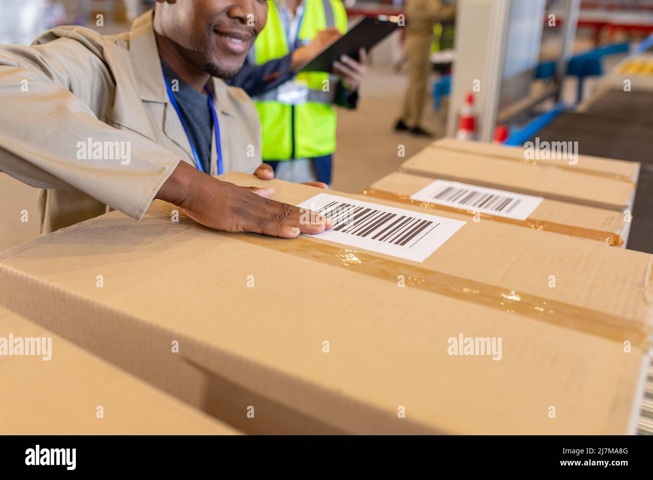 Sezione centrale di giovani lavoratori afroamericani che etichettano il codice a barre su scatola di cartone in magazzino Foto Stock