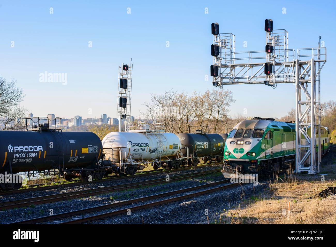 Una foto paesaggistica di una locomotiva diesel DEL treno GO Transit e di un treno merci che si affaccia sul porto di Hamilton sul sistema di transito ferroviario Metrolinx. Foto Stock