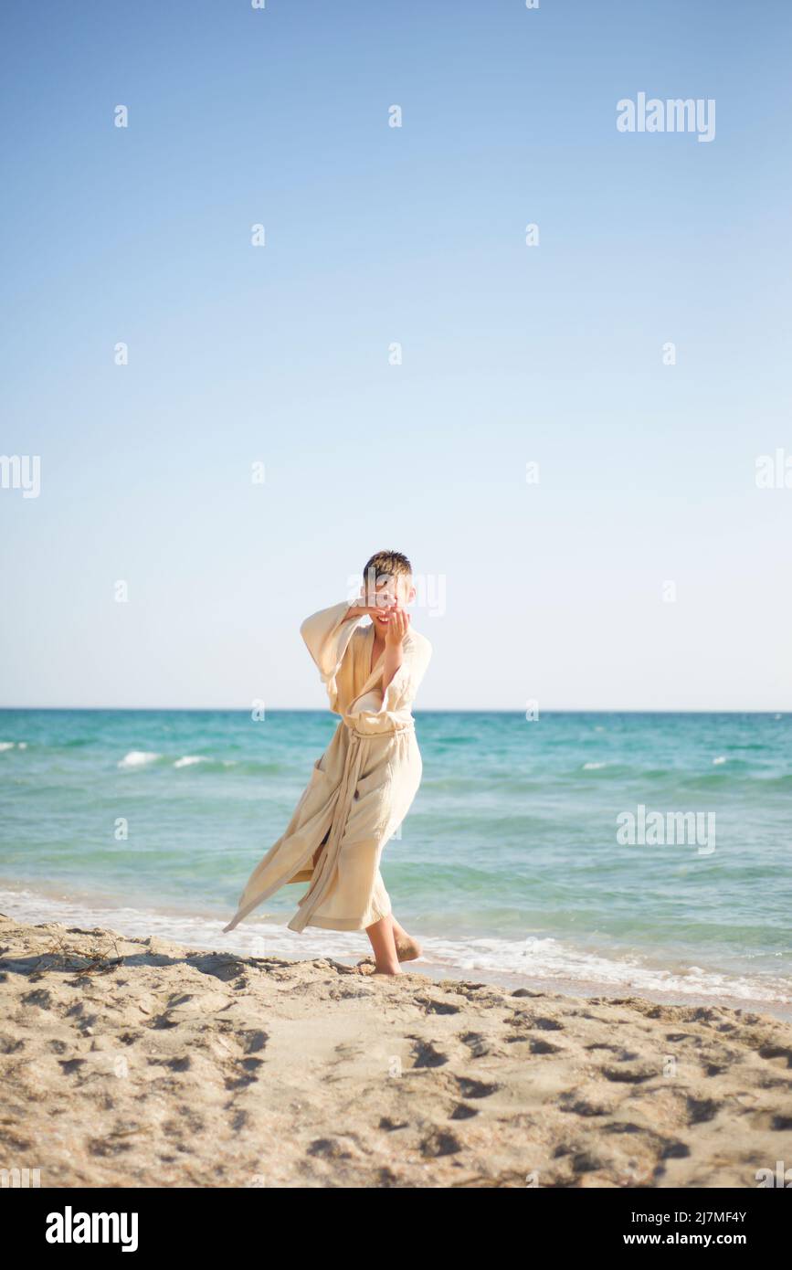 Pratica sulla spiaggia. Un ragazzo in un kimono sulla riva del mare. Balli. Esercizi respiratori orientali. Foto Stock
