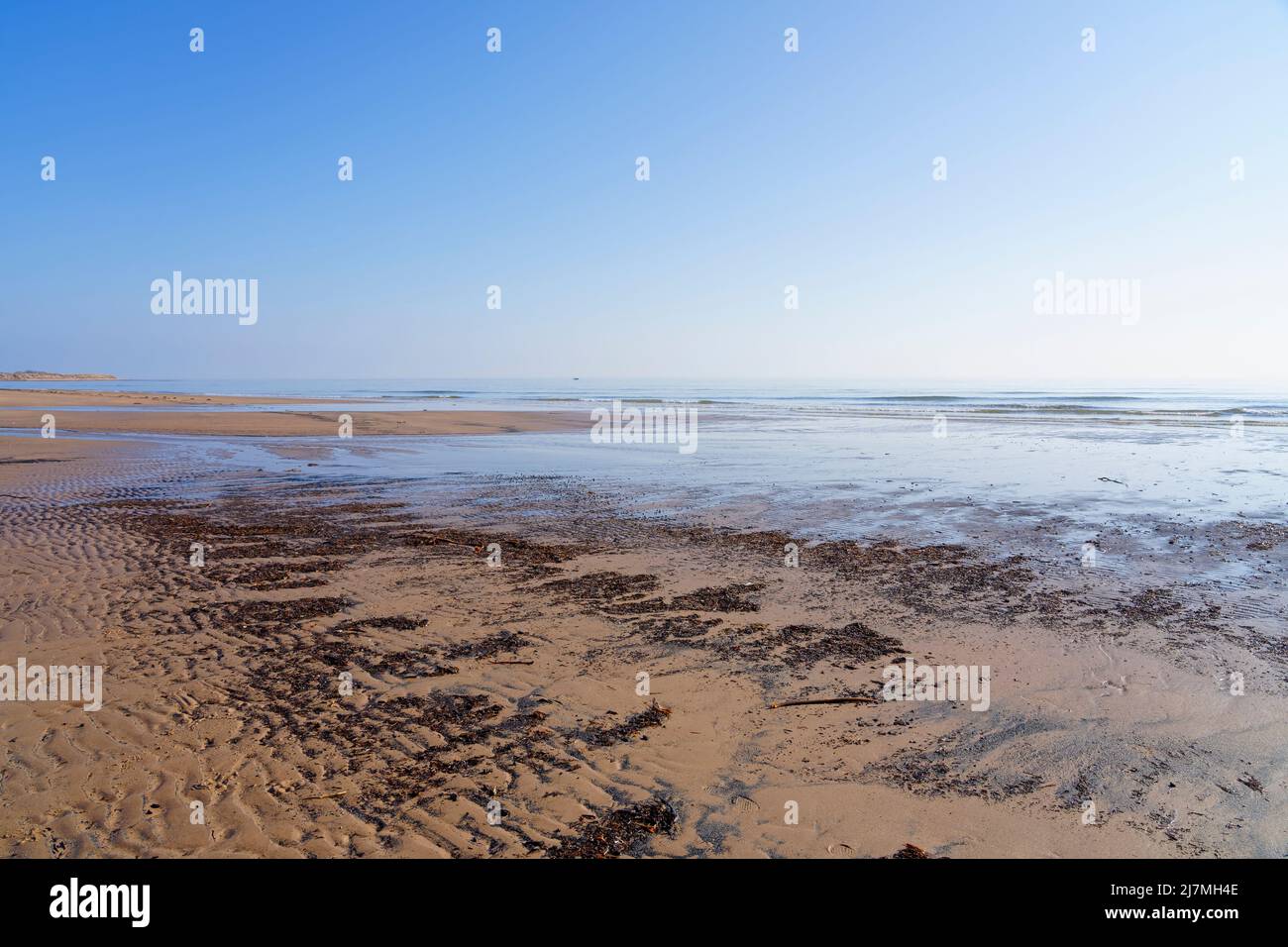Sulle sabbie ondulate di una spiaggia nella baia di Druridge a bassa marea sotto un cielo nuvoloso. Foto Stock