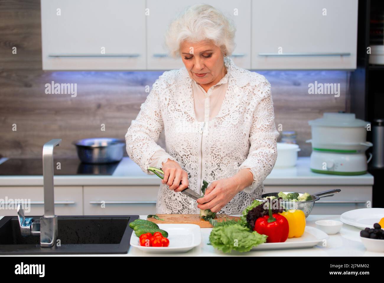 Donna caucasica pensionato taglia broccoli prima di cucinare Foto Stock
