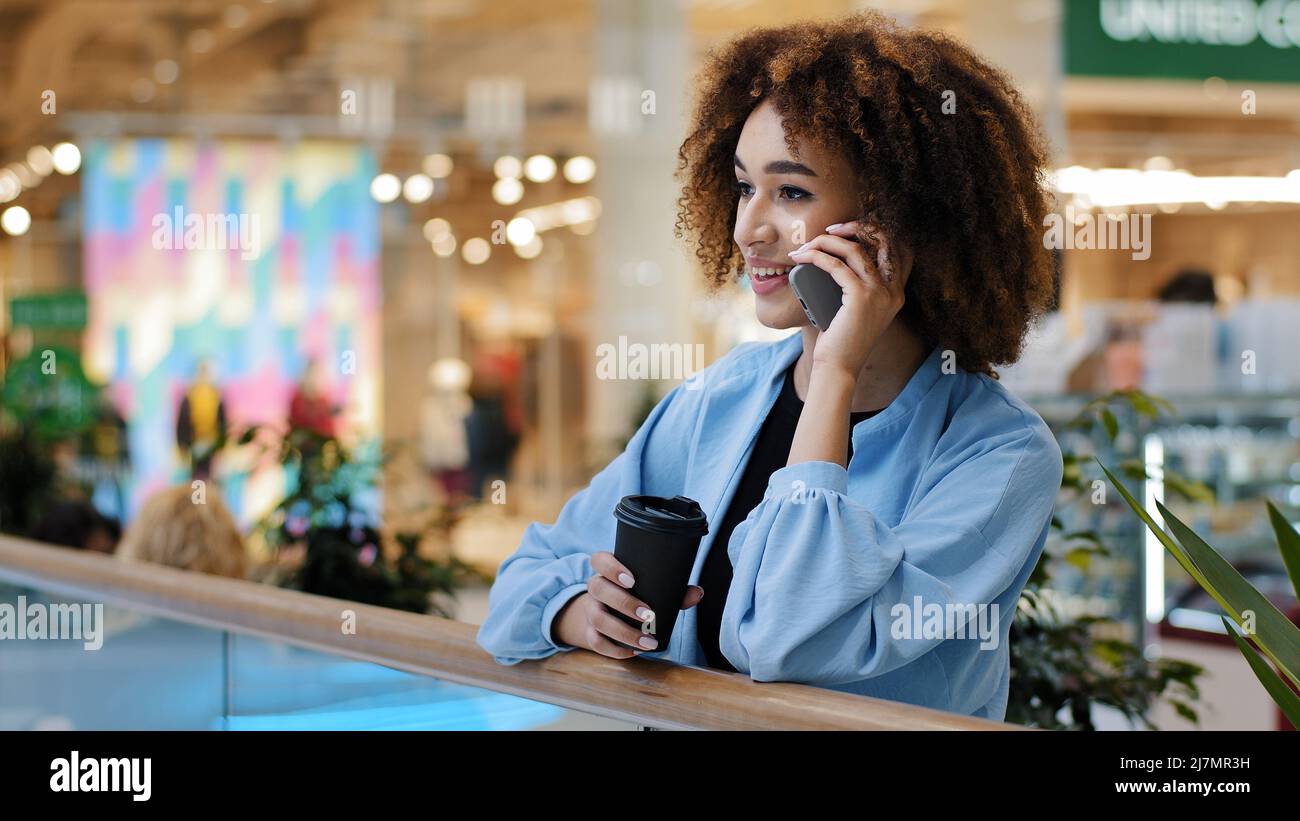 Donna d'affari afroamericana di successo che parla il telefono cellulare che risponde chiamata che chiama servizio di shopping online che fa l'ordine con smartphone Foto Stock