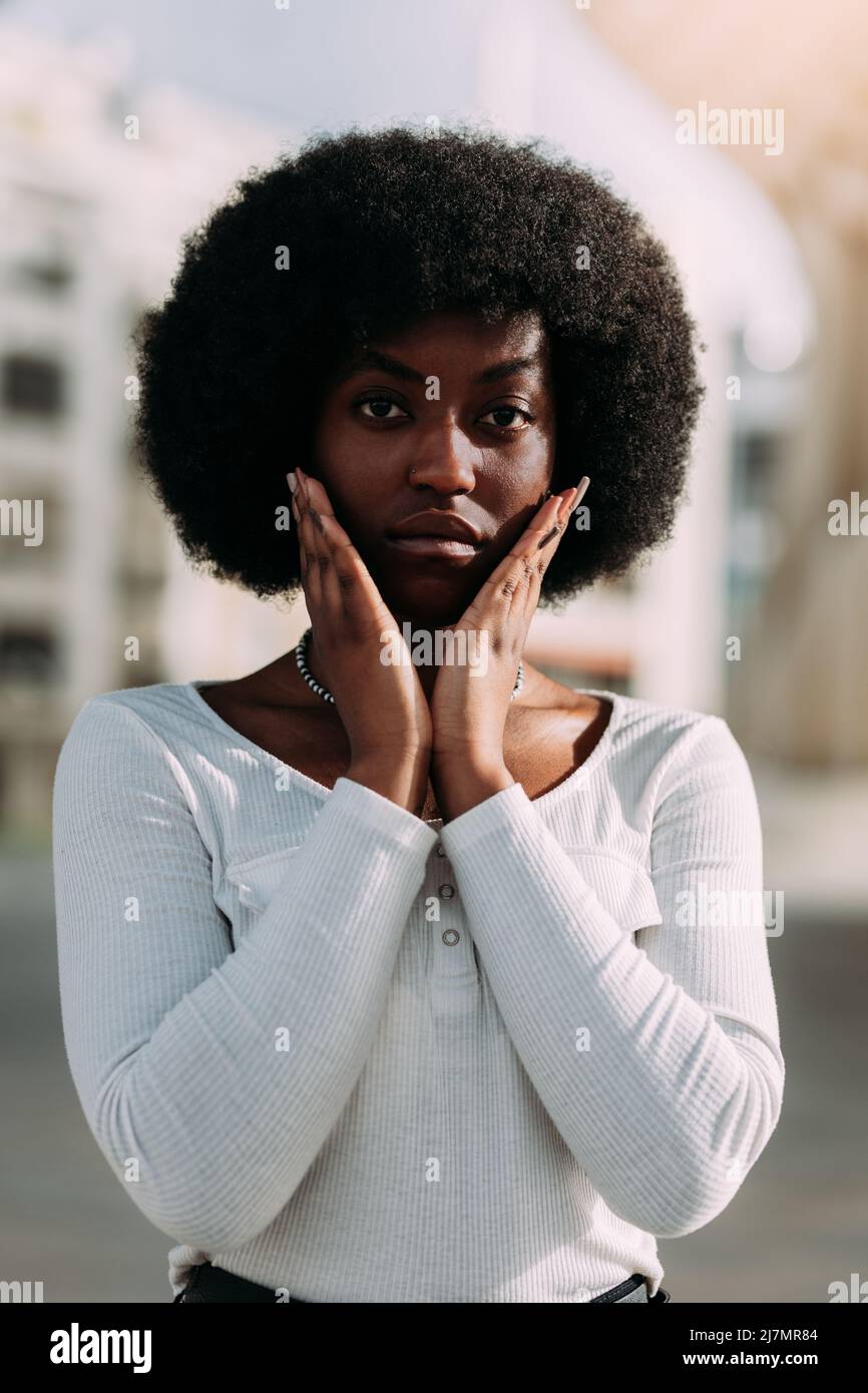 Ritratto di una giovane donna nera con capelli afro che gesturano con le mani a forma di V. Verticale Foto Stock