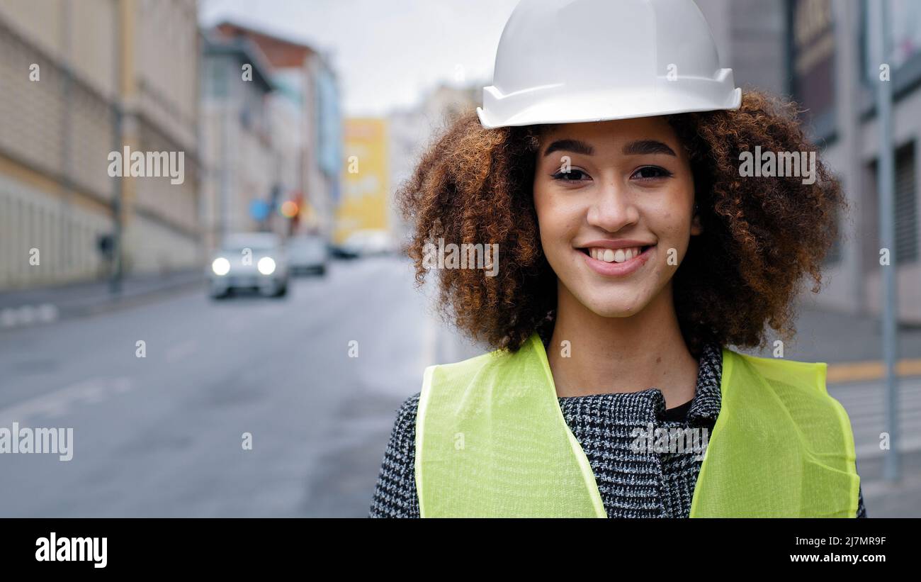 Donna ritratto lavoratore professione primo piano african american donna ragazza con capelli ricci ingegnere civile professionale indossare casco di sicurezza in piedi Foto Stock