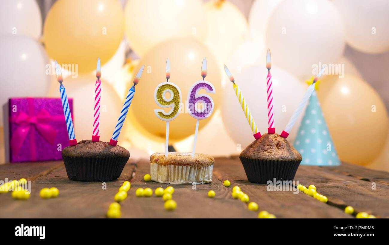 Bella carta di compleanno per una ragazza con un cupcake sullo sfondo di palloncini. Ragazza felice di compleanno, scatola del regalo sullo sfondo delle candele che bruciano. Foto Stock