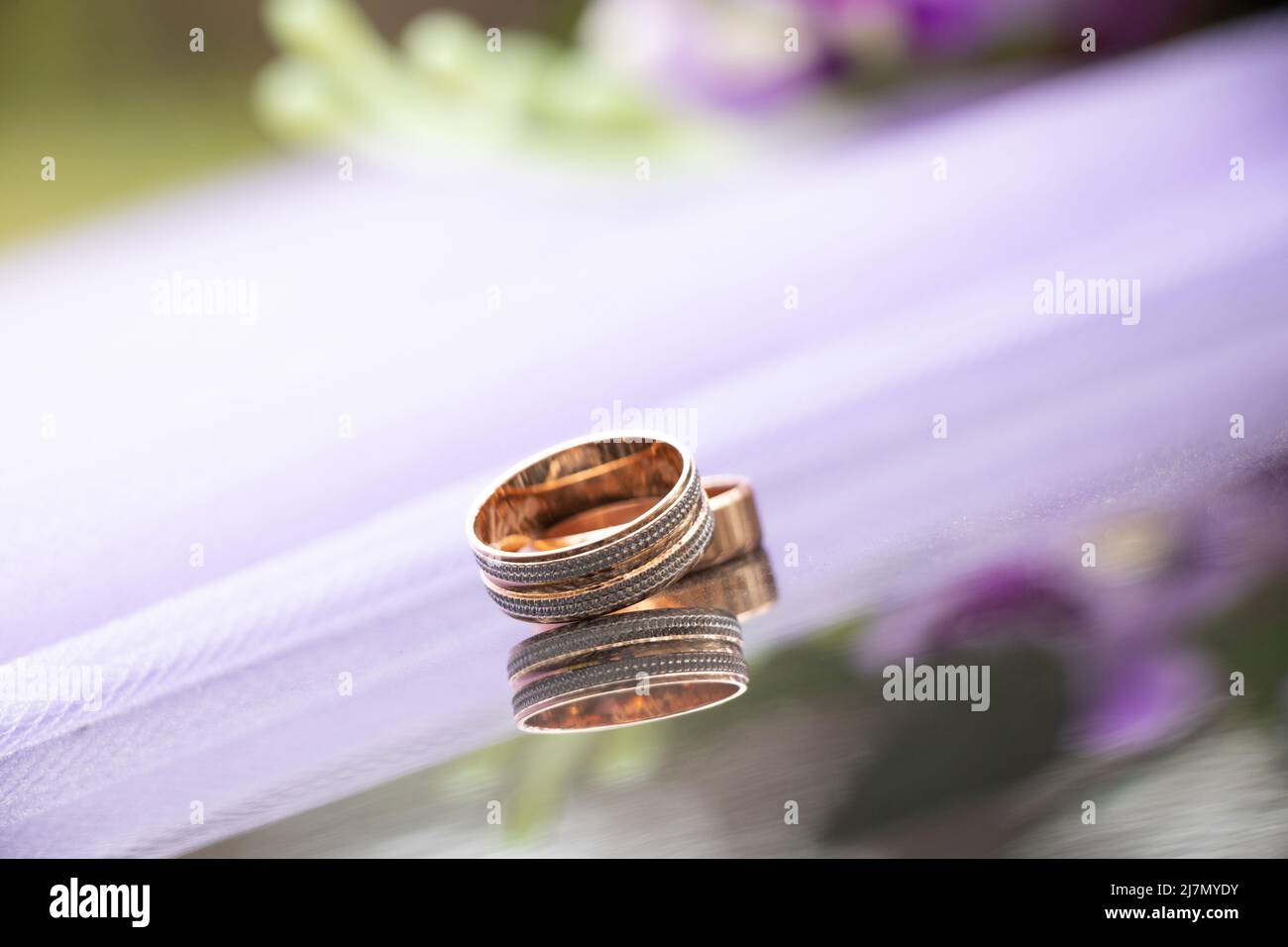 due anelli d'oro per matrimoni su sfondo scuro a specchio, anelli d'oro per matrimoni, matrimonio Foto Stock