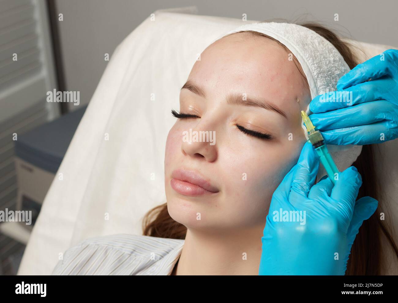 Siringa con plasma sanguigno di un paziente in una mano di un cosmetologo per un plasmolifting della pelle del viso di una donna. Plasma terapia, il ripristino delle cellule della pelle Foto Stock