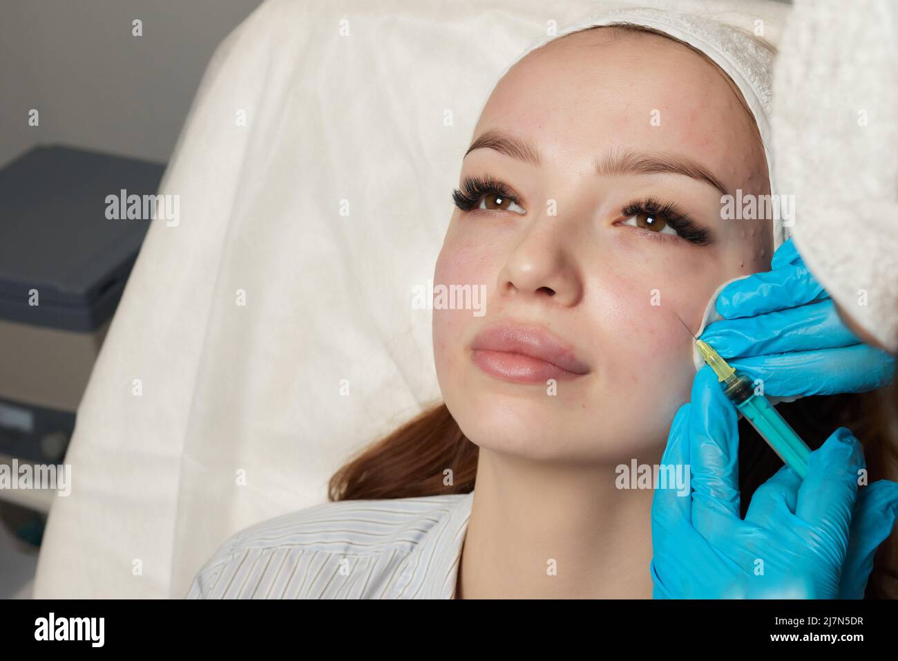 Siringa con plasma sanguigno di un paziente in una mano di un cosmetologo per un plasmolifting della pelle del viso di una donna. Plasma terapia, il ripristino delle cellule della pelle Foto Stock