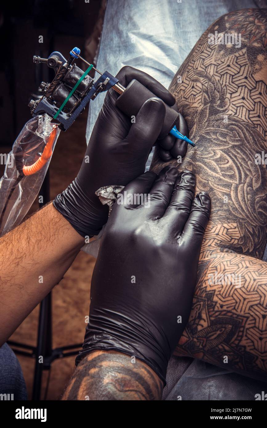 Specialista del tatuaggio che fa un tatuaggio in studio del tatuaggio./tatuista professionale fa il tatuaggio in salotto del tatuaggio. Foto Stock