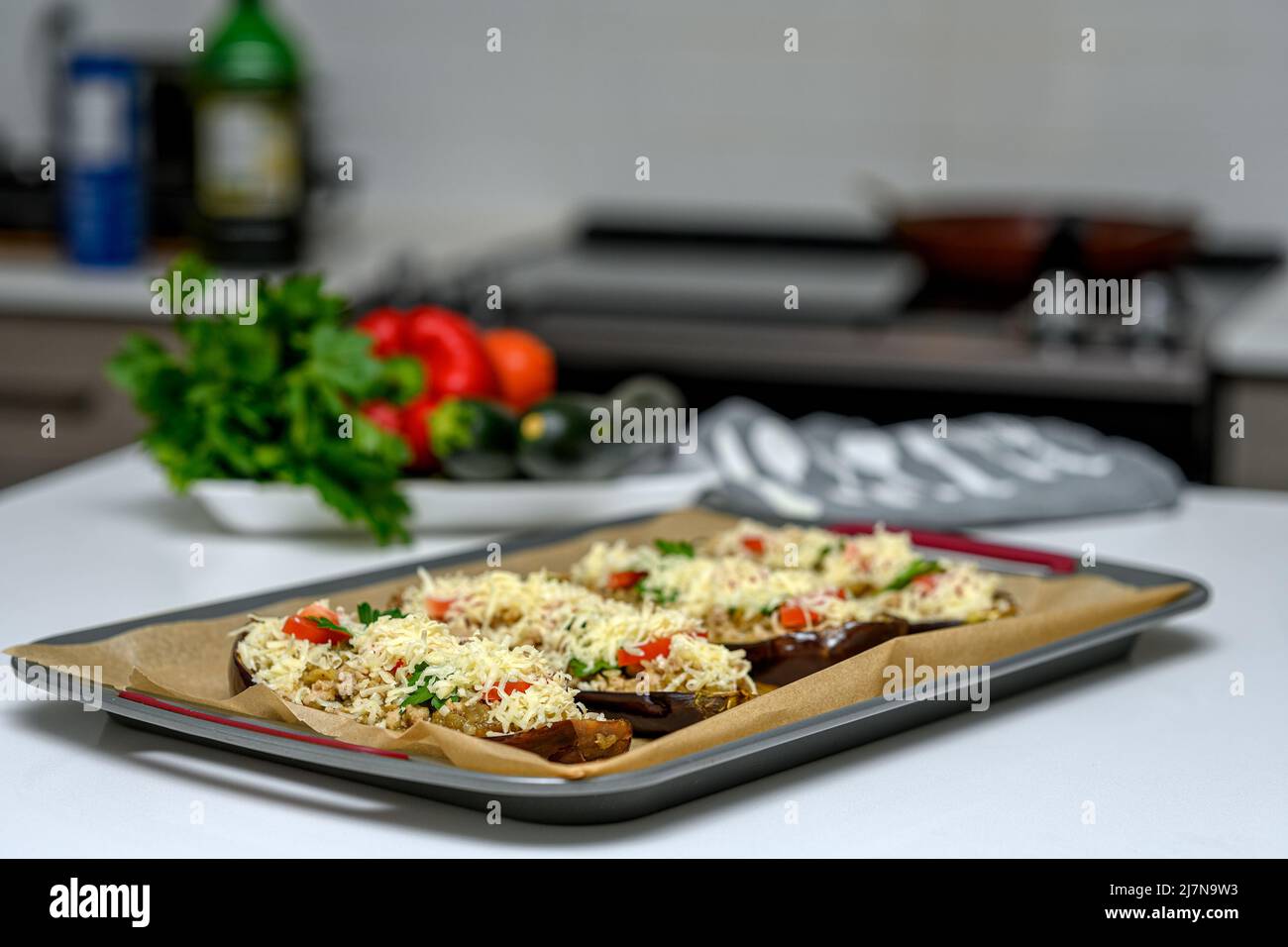 Donna caucasica in cucina preparare gli ingredienti per una cena sana. Ha posto le melanzane farcite su una teglia da forno in una padella arrosto e con la toma Foto Stock