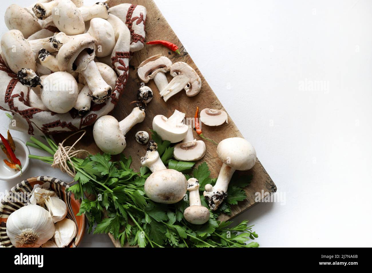 Funghi freschi di champignon e ingredienti per cucinare su sfondo bianco. Cucina funghi biologici. Direttamente sopra. Spazio di copia. Foto Stock