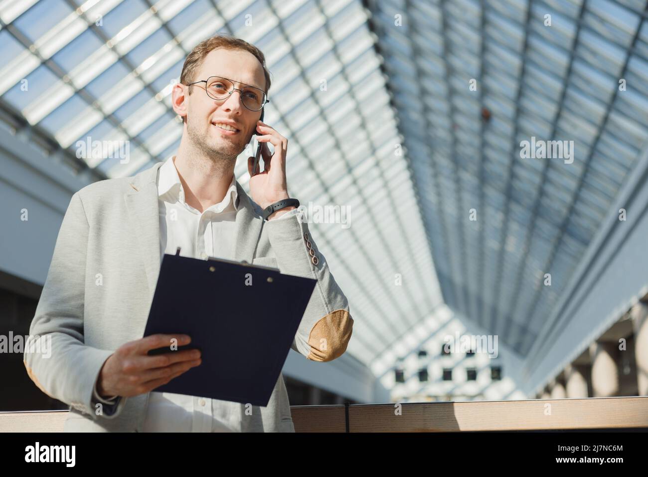 L'uomo in vestito con la cartella fa il sondaggio sul telefono, un sondaggio anonimo, le chiamate a freddo, la proposta di affari, le vendite. Foto Stock