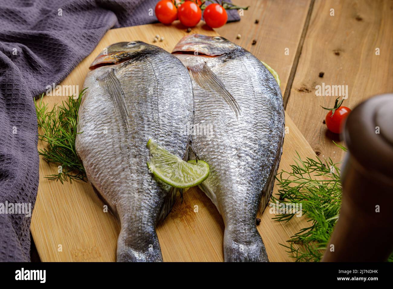 Pesce dorado sbucciato crudo con ingredienti da cucina. Pesce fresco su sfondo di legno. Foto Stock