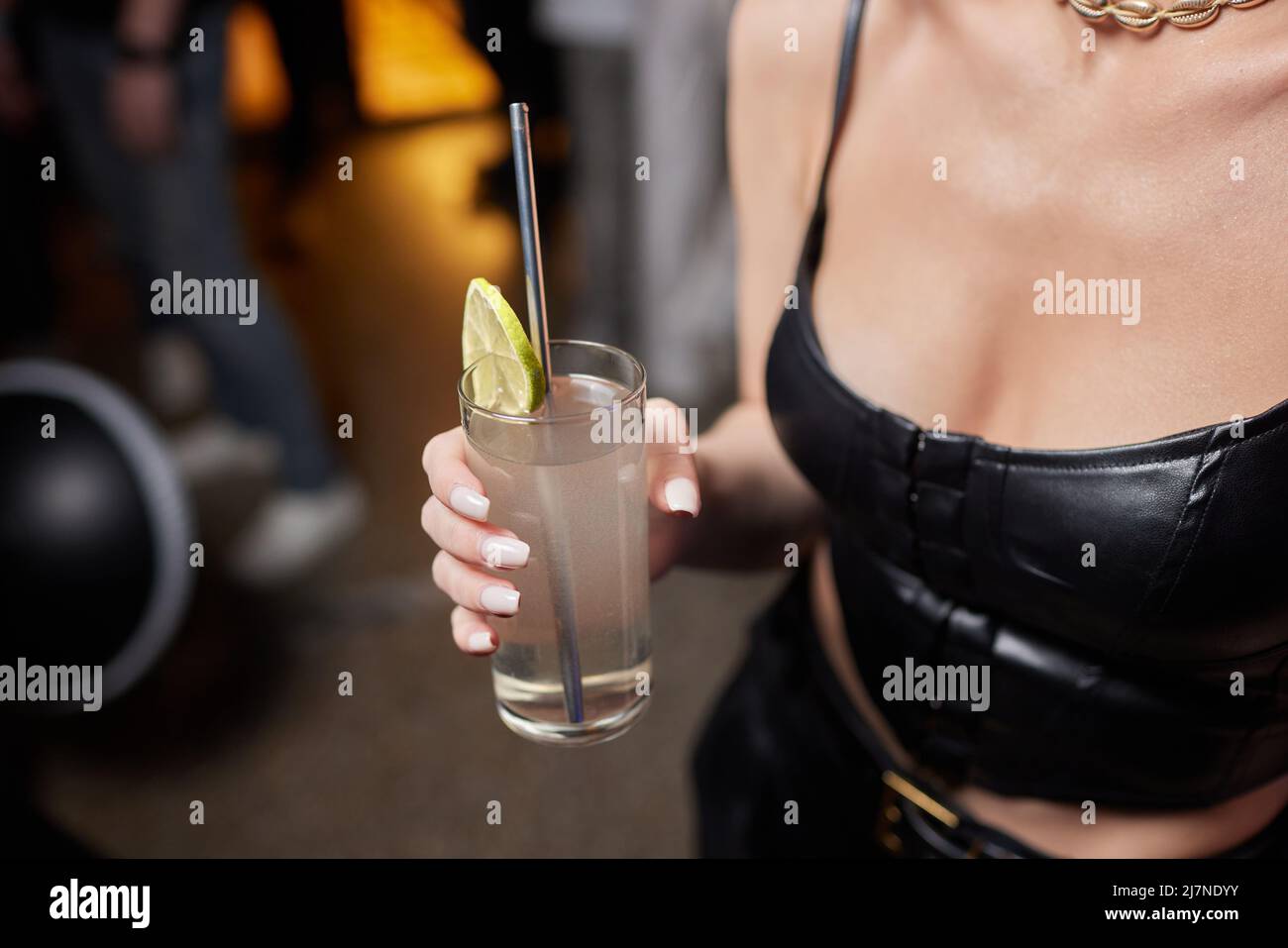 Primo piano immagine ritagliata di donna che tiene dolci cocktail gustosi limonata, elegante hipster outfit alla moda e gioielli eleganti, colori tonici, atmosfera da bar Foto Stock