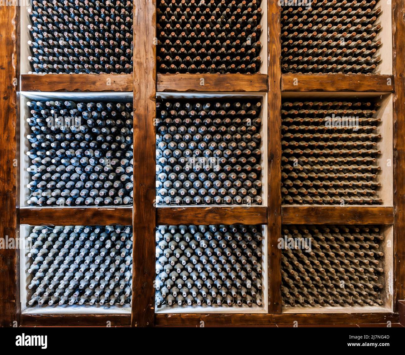 Vecchie bottiglie di vino che maturano in una cantina volta Foto Stock