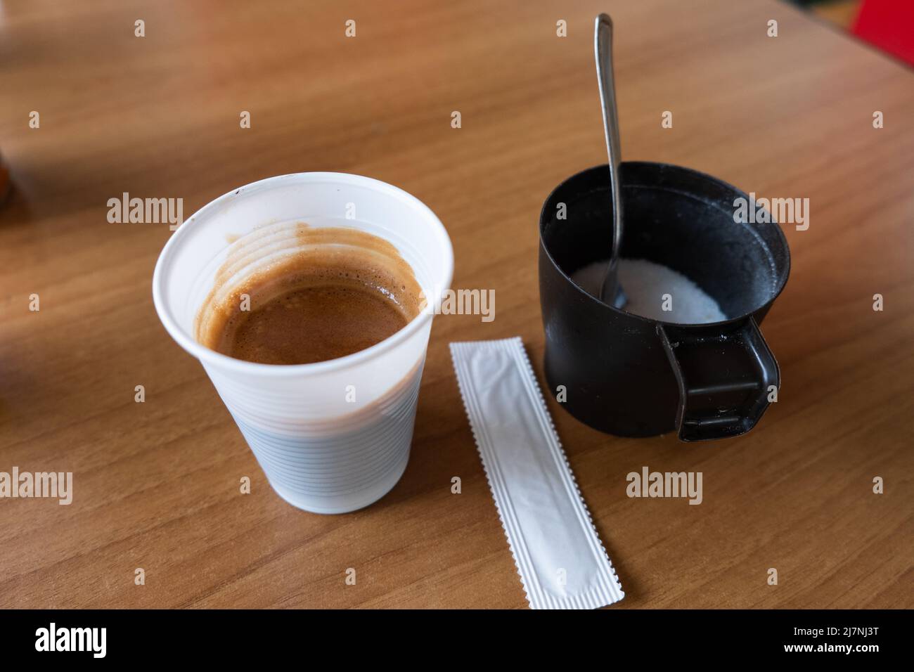 Semplice caffè normale in tazza di plastica servito con zucchero bianco. Caffè espresso italiano o caffè normale. Foto Stock