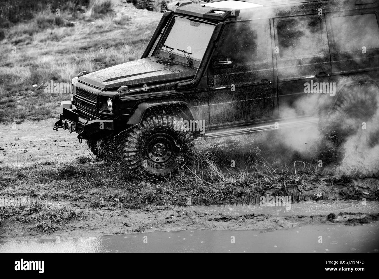 Spedizione fuoristrada in jeep verso i villaggi sulla strada di montagna. Classica vettura 4x4 che attraversa l'acqua con spruzzi su strada fangosa. Auto fuoristrada. Foto Stock