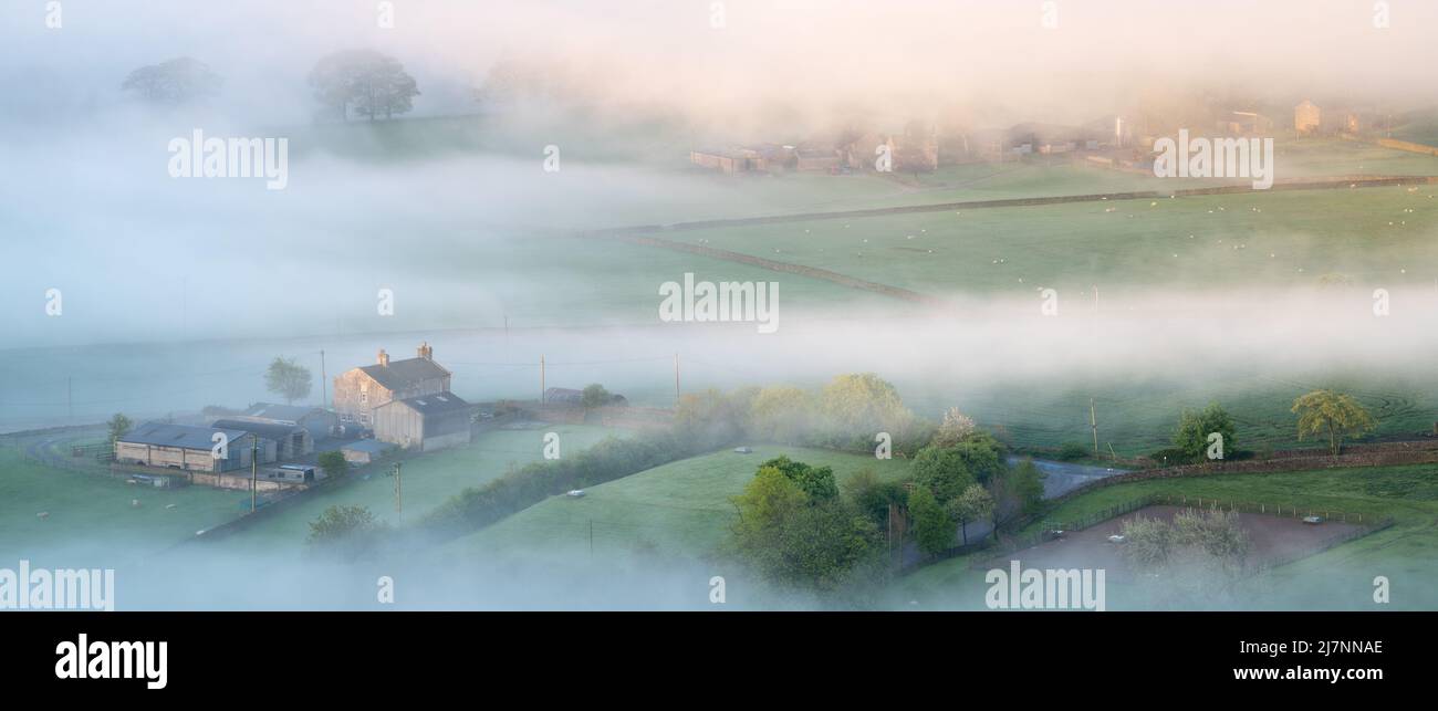 Accenni del paesaggio patchwork sotto Embsay Crag sono visibili come la nebbia si abbra e scorre in una bella mattina di primavera nel North Yorkshire. Foto Stock