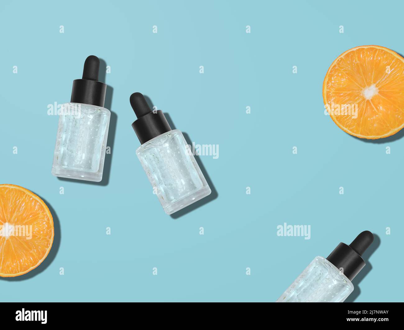 Bottiglie cosmetiche in vetro e arance su sfondo blu Foto Stock