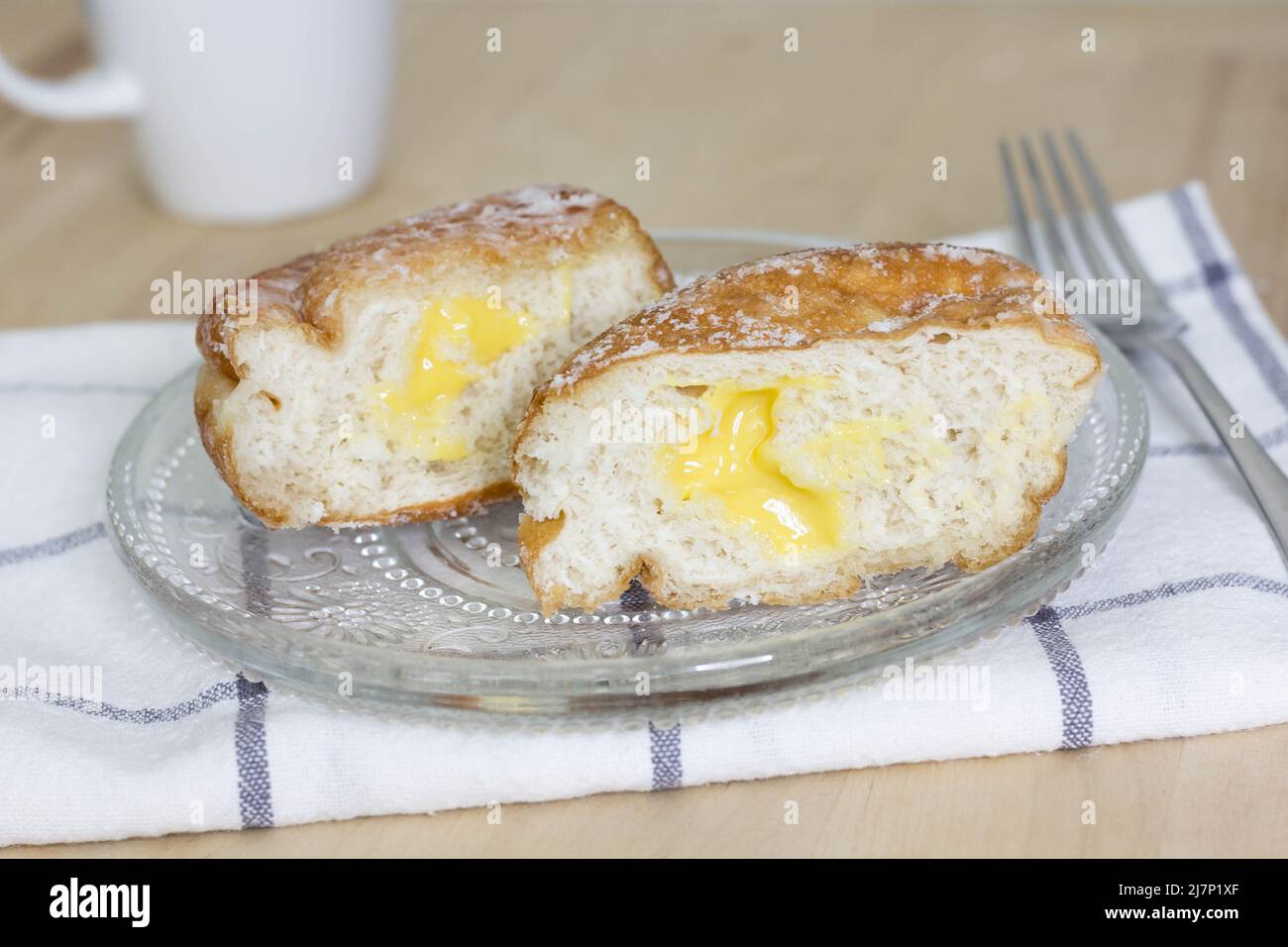 Ciambella fritta (paczki o sisky) con ripieno di crema al limone, ciambella al limone tagliata a metà - fuoco selettivo Foto Stock