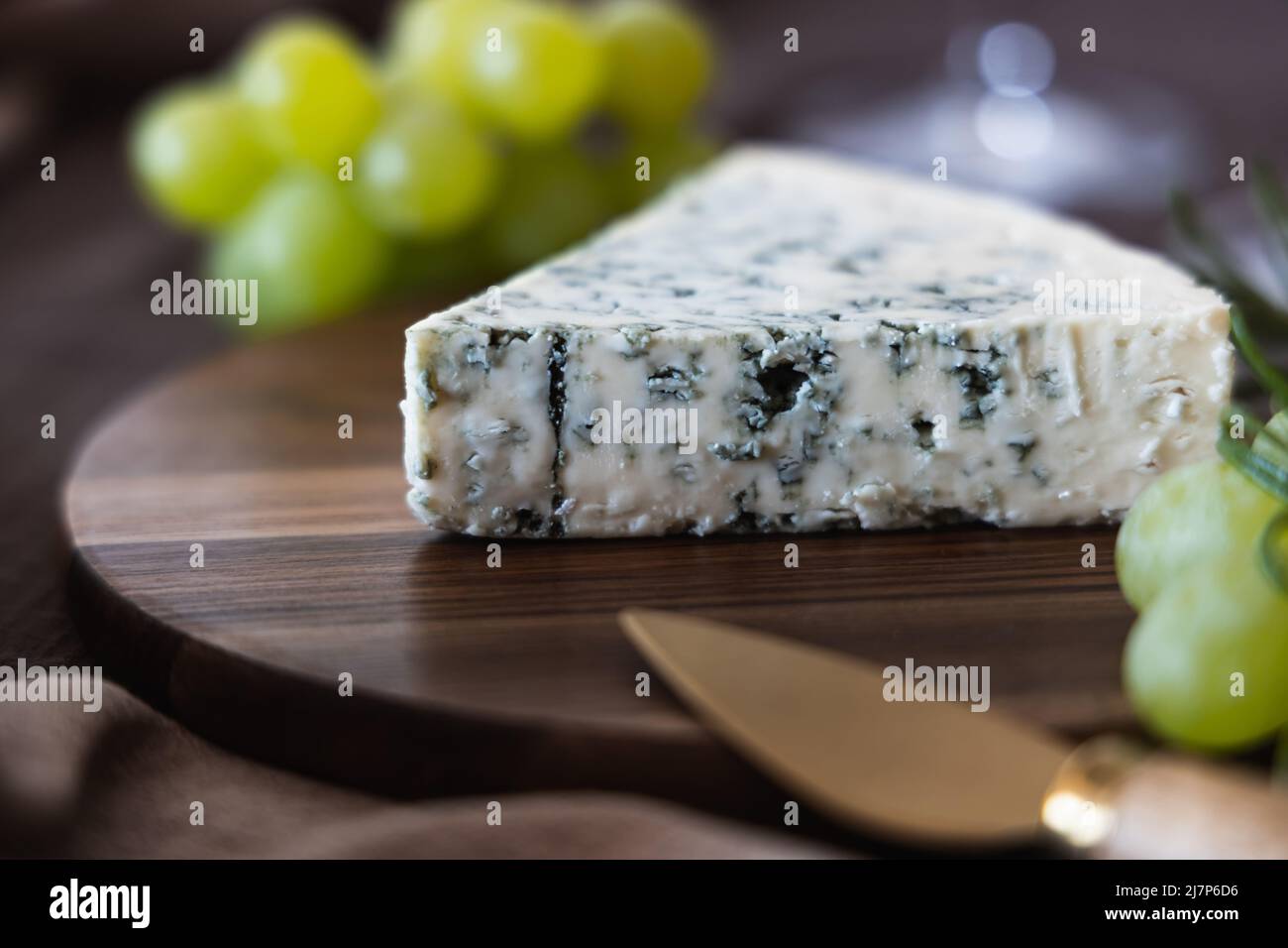 Formaggio blu con un coltello da formaggio su un asse di legno. Foto Stock