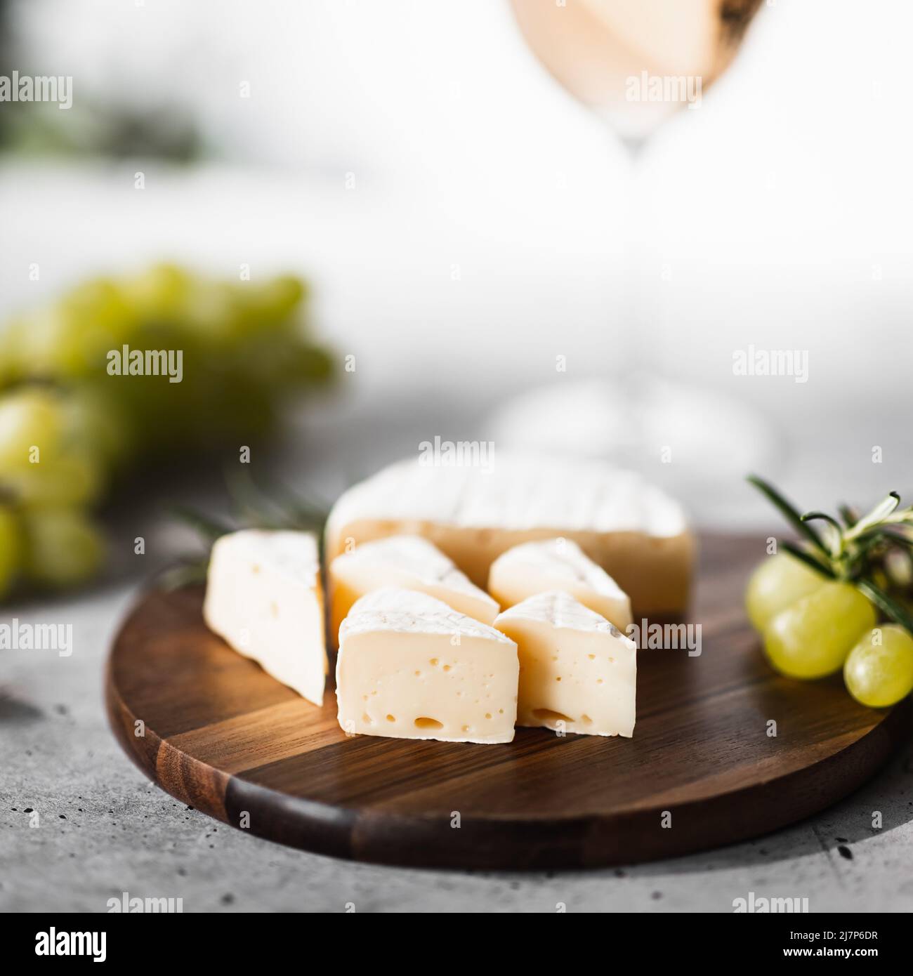 Formaggio Camembert su un asse di legno. Sullo sfondo un bicchiere di vino. Foto Stock
