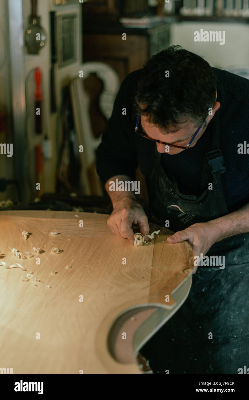 scultura luthier che crea trucioli di legno su un tavolo frontale a doppio basso Foto Stock
