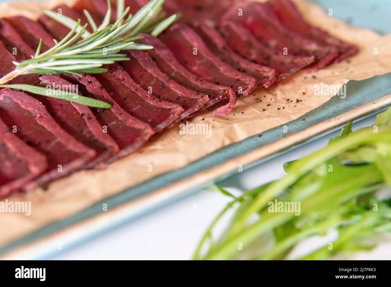 pastrami su un piatto blu con pomodori ciliegini Foto Stock