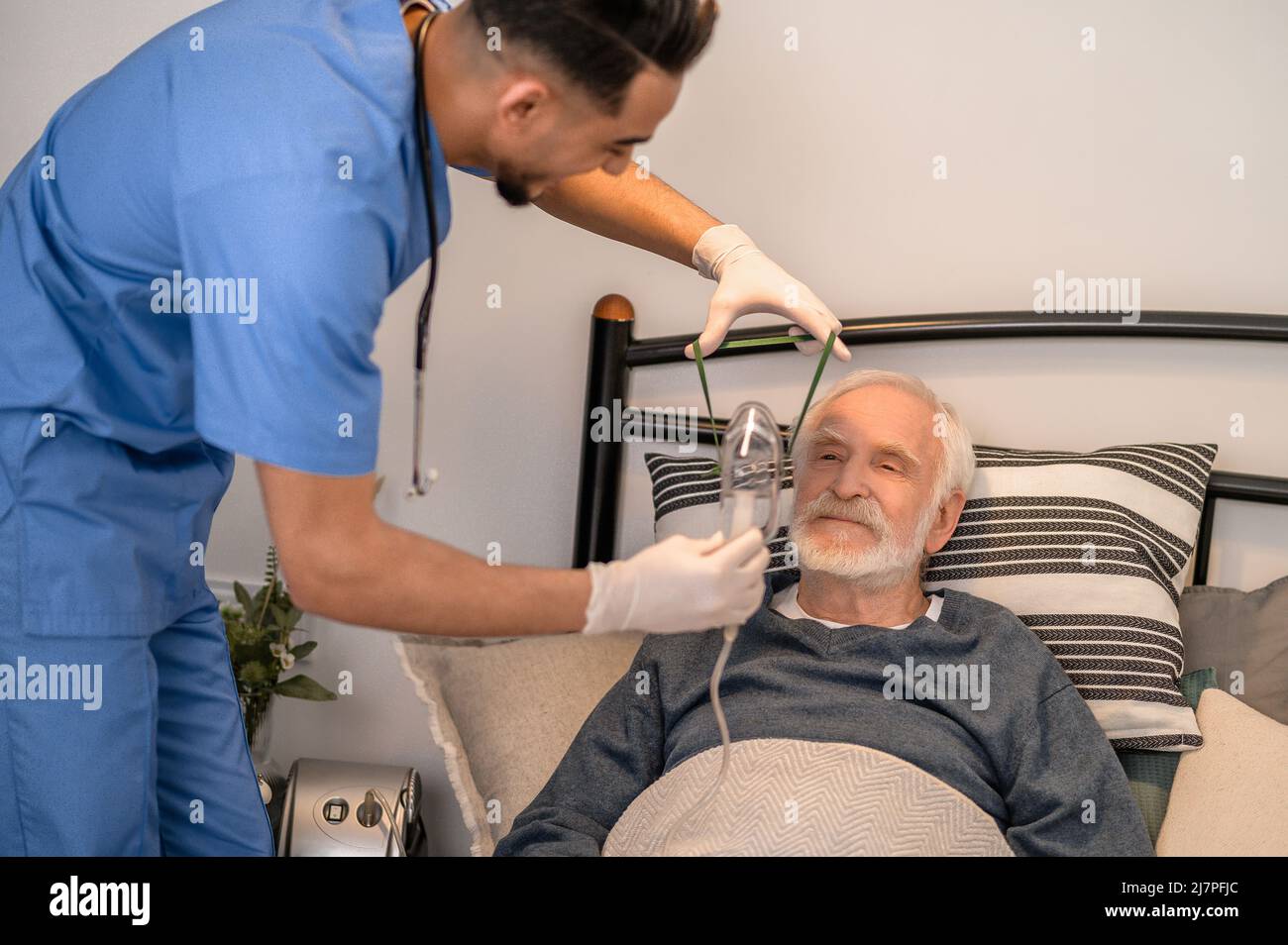 Infermiera che prepara un uomo anziano per l'ossigenazione Foto Stock