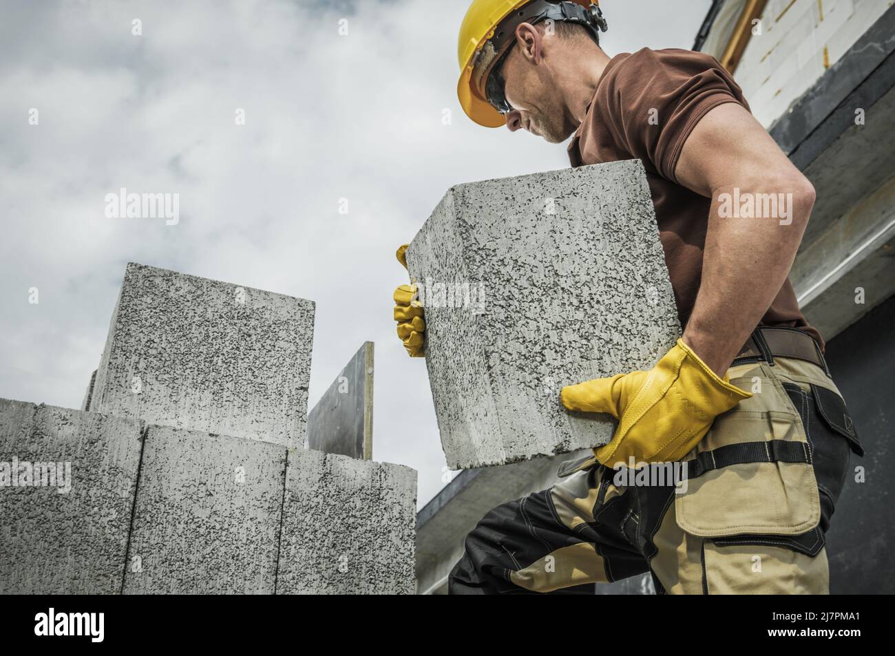 Blocchi di calcestruzzo densi cavi spostati dal lavoratore dei cantieri caucasici. Edilizia residenziale. Foto Stock