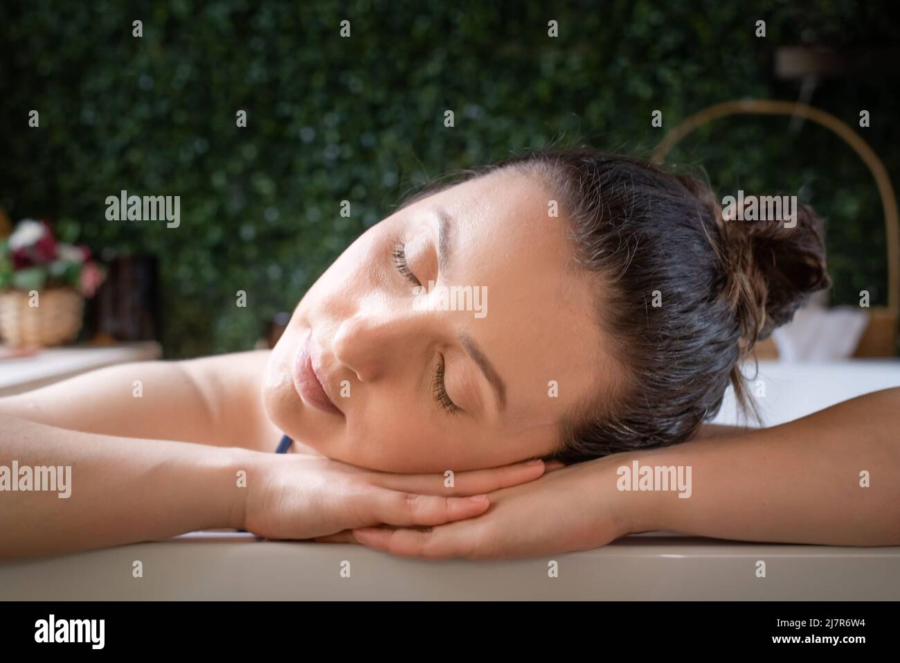 Rilassato Donna riposo testa nelle mani in vasca idromassaggio Foto Stock